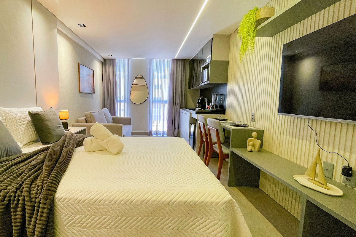 Ein modernes Hotelzimmer mit einem großen Bett, einem Schreibtisch, einem Fernseher und einer Küchenzeile.
