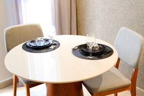 A round dining table with two chairs, each with a placemat and a wine glass. - Acqua Tambaú Comfort II - By Almare (João Pessoa)