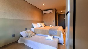 Quarto de hotel com duas camas, um ar condicionado e uma porta que dá para outro quarto.