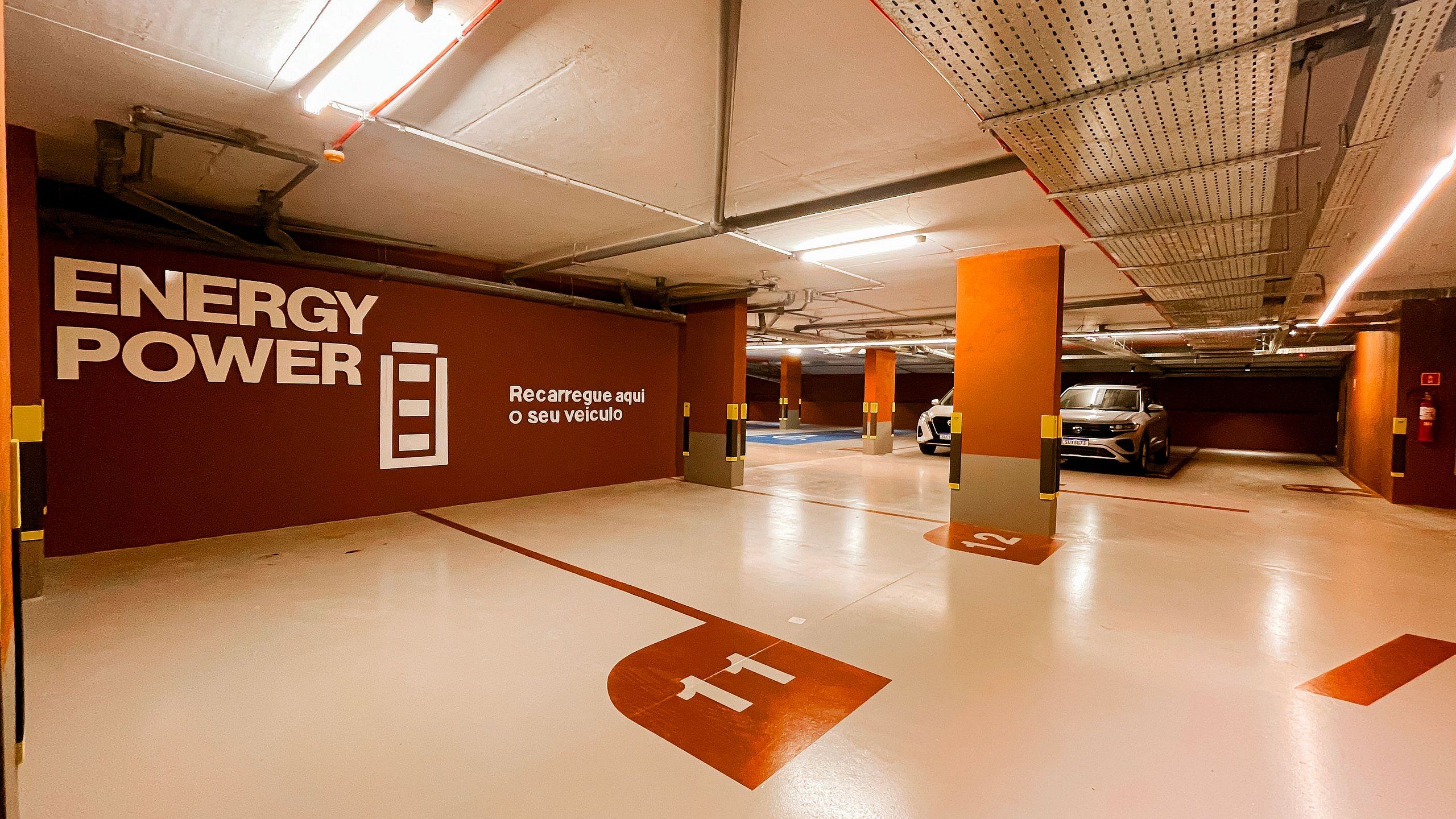 A parking garage with 'ENERGY POWER' signage, clear floor markings, and a vehicle in the background.