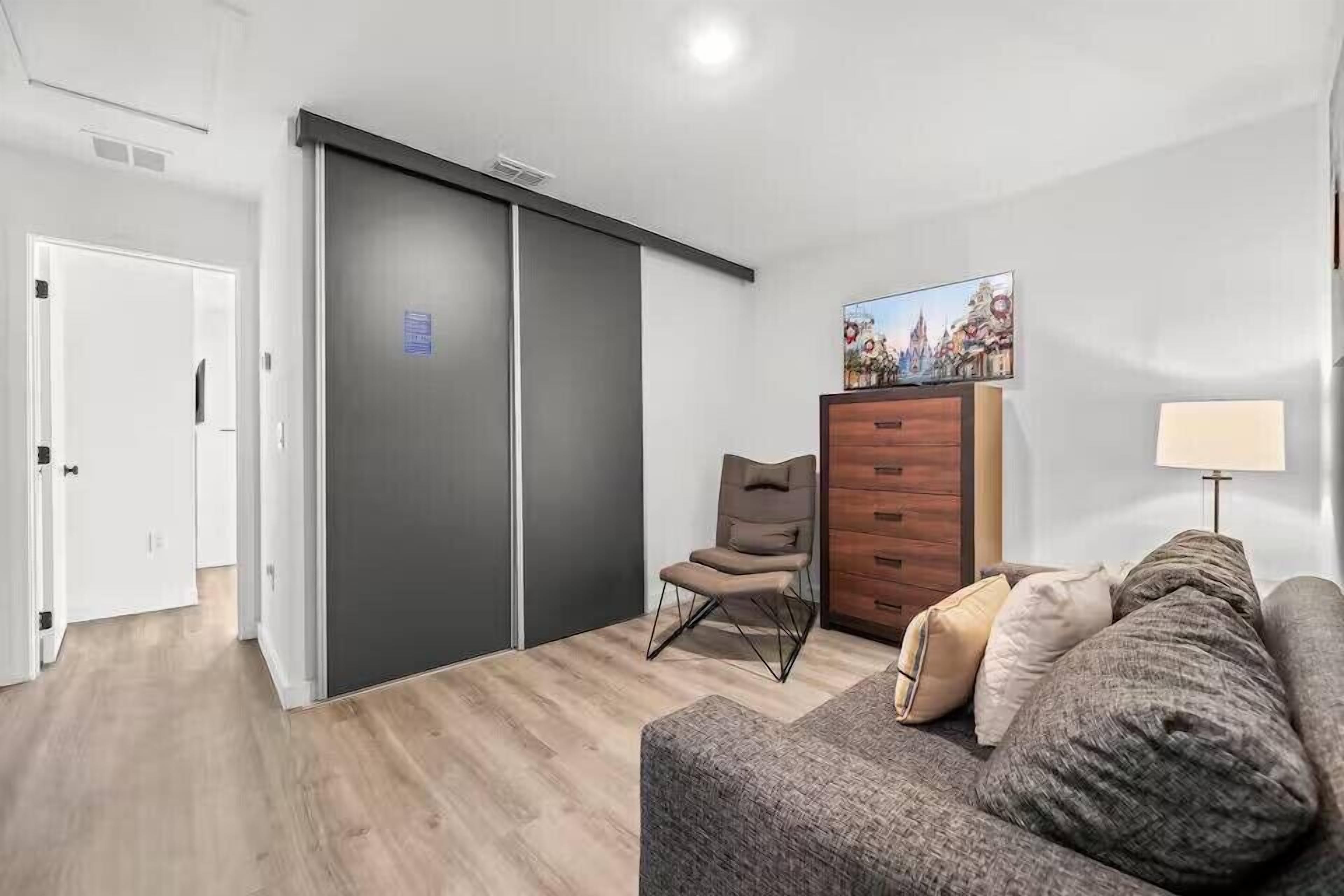Un salon moderne avec un canapé, un fauteuil, un meuble en bois et un tableau accroché au mur.