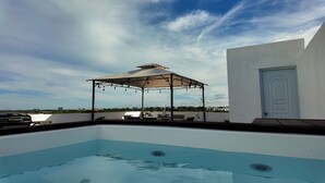 Ein Pool auf dem Dach mit einer Pergola, Liegestühlen und einer Tür.