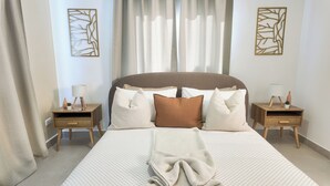 A neatly arranged bedroom with a large bed, two bedside tables with lamps, and decorative wall art. - Oasis del Caribe - Jacuzzi & Rooftop Retreat (Punta Cana)