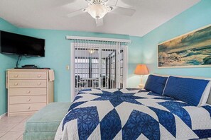 Ein Schlafzimmer mit einem Bett, einem Schminktisch, einem Fernseher, einem Gemälde und einem Deckenventilator.