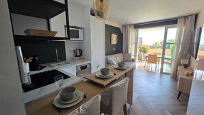 Eine moderne Küche mit Essbereich, einer Couch und Blick ins Freie.