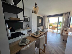 Eine moderne Küche mit Essbereich, einer Couch und Blick ins Freie.