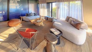 A modern living room with a sofa, coffee table, and a red chair. - Loft Elegance 2 bed | Gym • Pet Friendly • AC (Guadalajara)