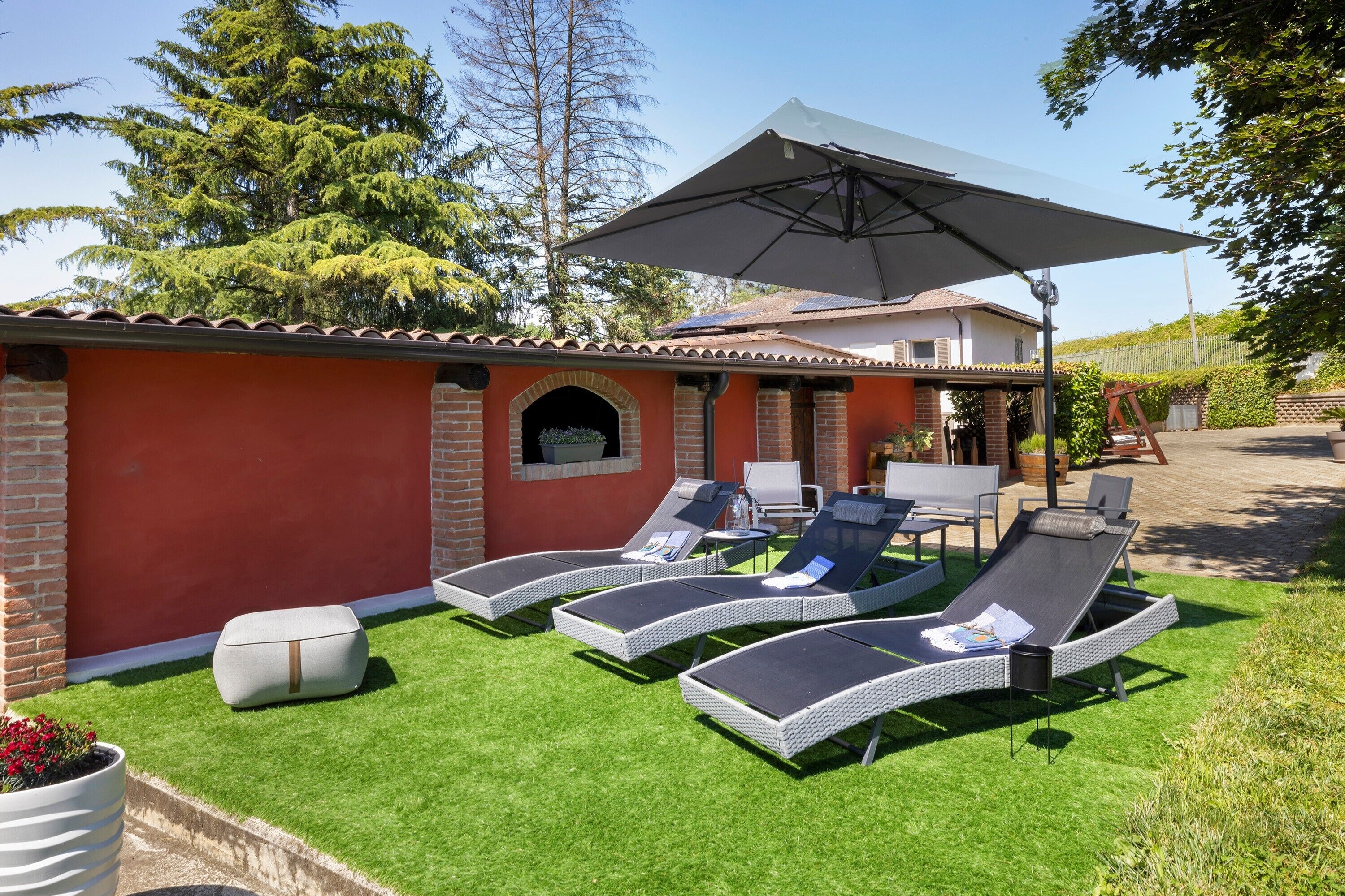 A patio with lounge chairs, a table, and a large umbrella.