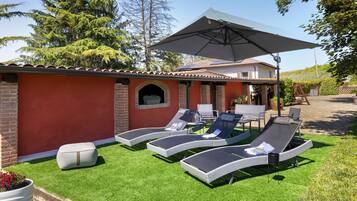 A patio with lounge chairs, a table, and a large umbrella.
