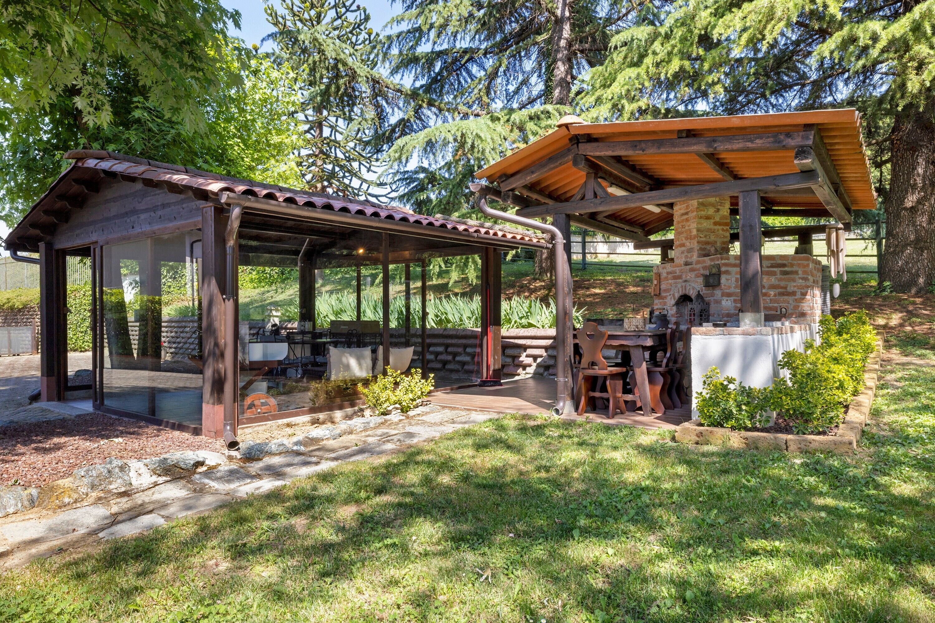 A covered outdoor seating area with a brick structure, stone pillars, and a wooden roof.