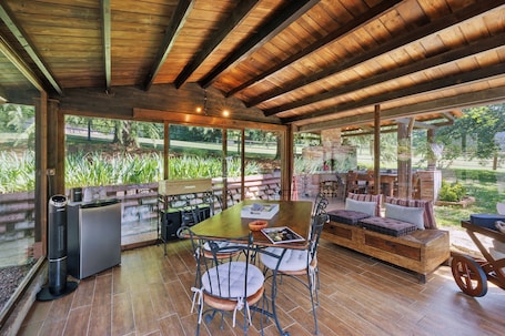 An outdoor dining area with a wooden table and chairs, a built-in bench, and a view of a garden.. Villa Paradiso Apartment with Private Pool, Garden and Wi-Fi