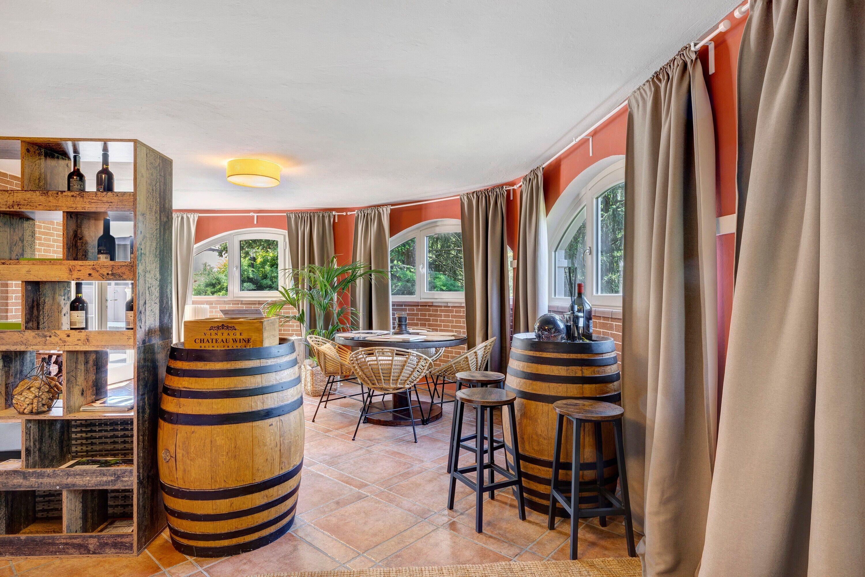 A restaurant with wooden barrels, wicker furniture, and a brick wall.