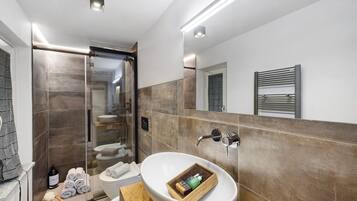 A modern bathroom with a large white sink, a glass shower enclosure, and a towel rack.