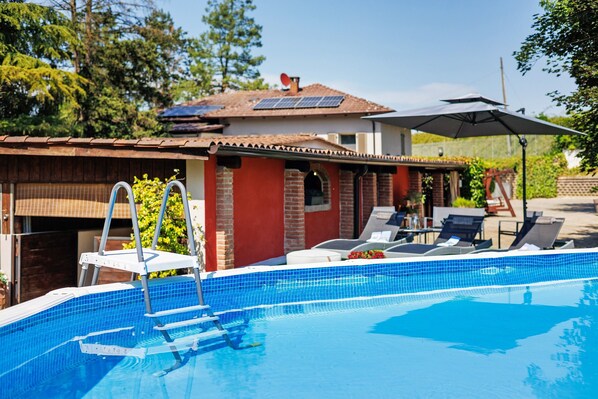 En pool med stige, liggestole og parasol.