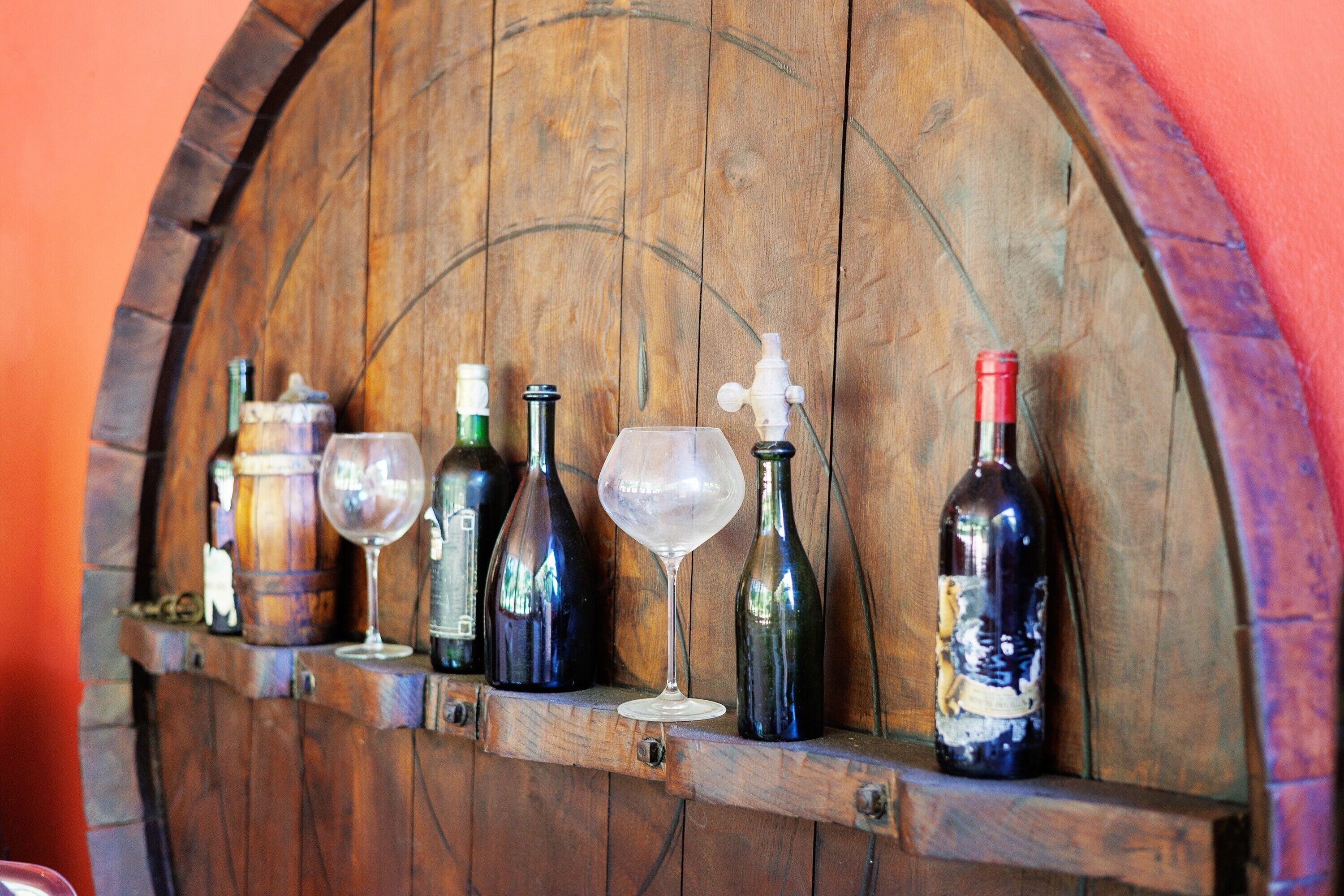 A wooden wine rack with various bottles and glasses.