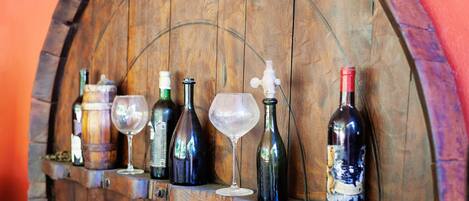 A wooden wine rack with various bottles and glasses.