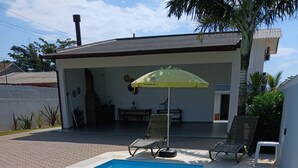 Una piscina con sillones de descanso y una sombrilla.