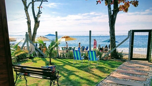 Un patio frente a la playa con una banca, sillas y un camino que lleva a la orilla.