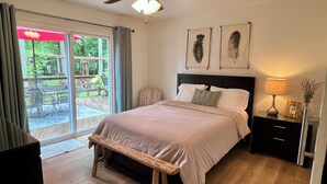 A bedroom with a bed, a nightstand, a lamp, a ceiling fan, and a view of the outdoors through a sliding glass door. - Woodland Edge Retreat- Borders NRG National Park, trail access from backyard (Fayetteville)