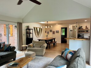 Ein großzügiger Wohnbereich mit Sofa, Couchtisch und Esstisch. Es gibt eine K üchenzeile mit Arbeitsplatte und Regalen.