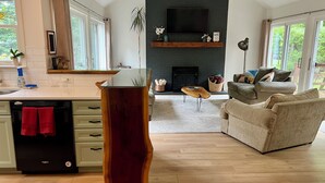 A modern kitchen with a dishwasher, a wooden island, and a dining area with a table and chairs. - Woodland Edge Retreat- Borders NRG National Park, trail access from backyard (Fayetteville)