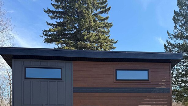 A modern building with a flat roof, large windows, and a wooden deck.