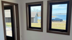 A room with a wooden floor, three windows, and a ceiling light.