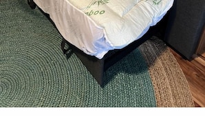 Una cama con un edredón con motivos de bambú, un cabecero de madera y una alfombra verde con textura.