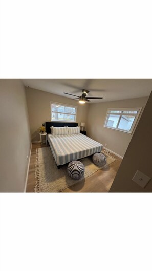 A bedroom with a bed, a ceiling fan, a window, and a rug.