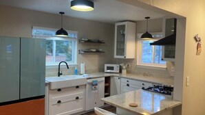 Una cocina moderna con gabinetes blancos, microondas integrado y estufa a gas.