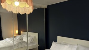 A hotel room with two beds, a hanging lamp, and a dark wall. - Wiltern Court (London)