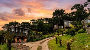 A resort with multiple wooden cabins, a paved pathway, and lush greenery. - Chalet Paradise (Bom Jardim da Serra)