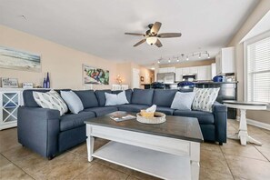 Ein modernes Wohnzimmer mit einem Ecksofa, einem Couchtisch und einem Deckenventilator.