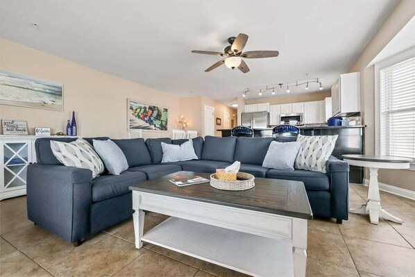 A modern living room with a sectional sofa, a coffee table, and a ceiling fan.