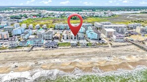 A coastal residential area with multiple buildings, a beachfront, and a red location marker.