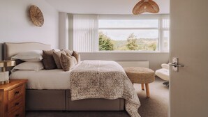 Une chambre à coucher comprenant un lit, une table de chevet, une lampe, une fenêtre avec vue et un luminaire suspendu.
