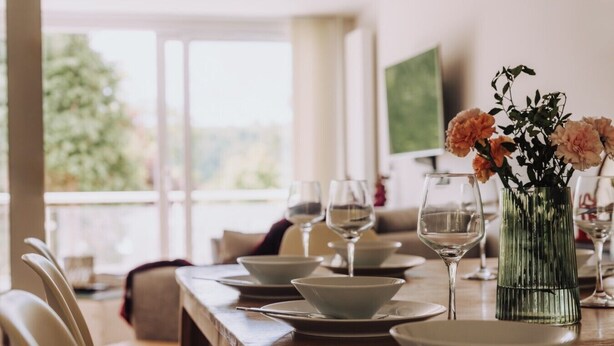 Un coin repas avec une table en bois mise pour un repas, comprenant des assiettes, des bols et des verres à vin.