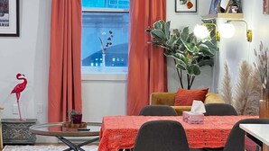 A dining area with a table set for four, a potted plant, and a red curtain. - Flamingo Grove, Vibrant Downtown Studio Escape, AC (Halifax)