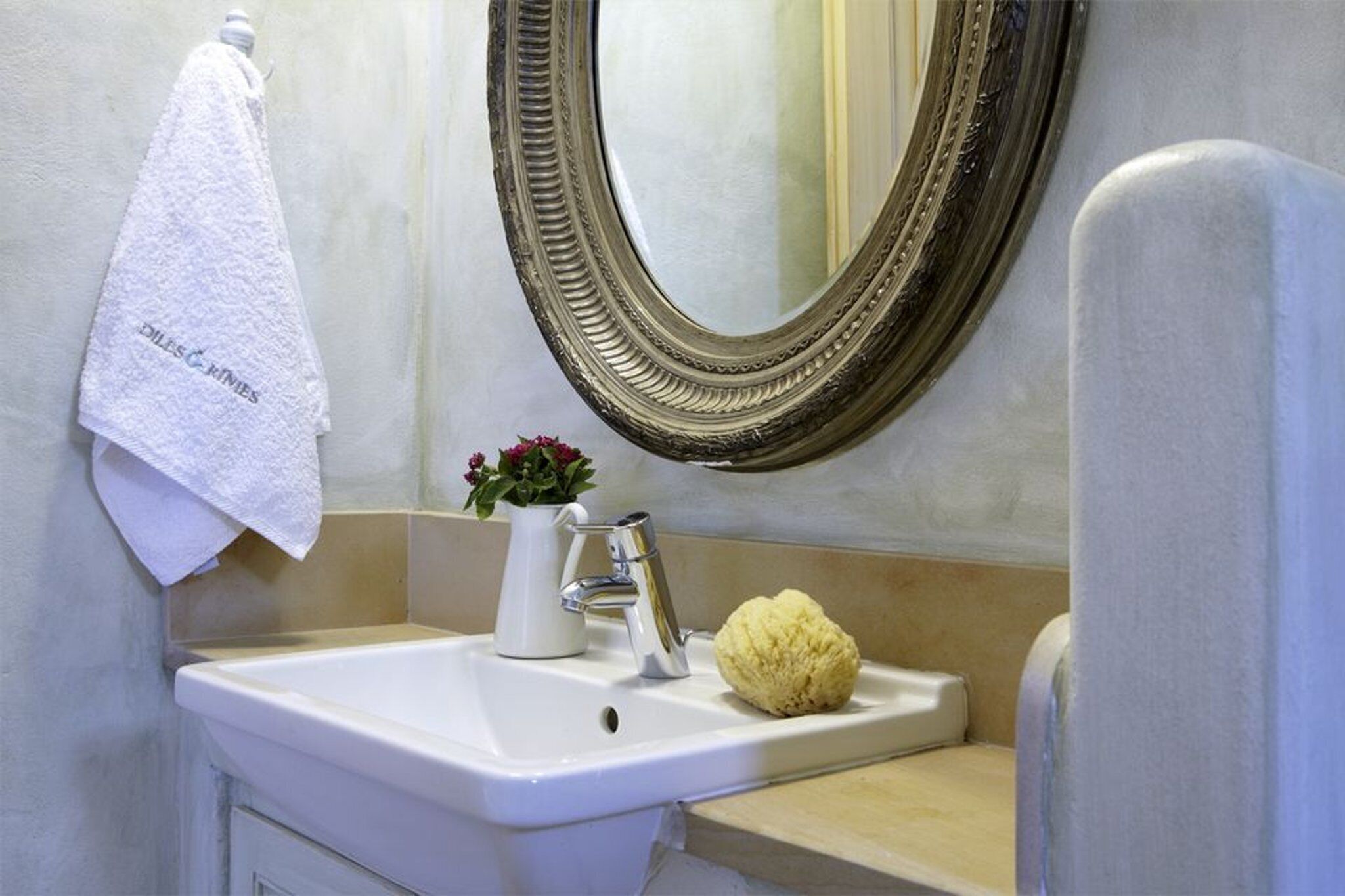 Une salle de bain avec un lavabo, un miroir, une serviette et une plante en pot.