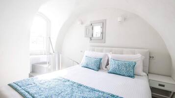 Une chambre à coucher avec un lit, des murs blancs, une fenêtre et un escalier.