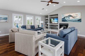 A living room with a sofa, coffee table, TV, and fireplace. - Grand Canalside Direct access 2 blocks to beach (Marco Island)
