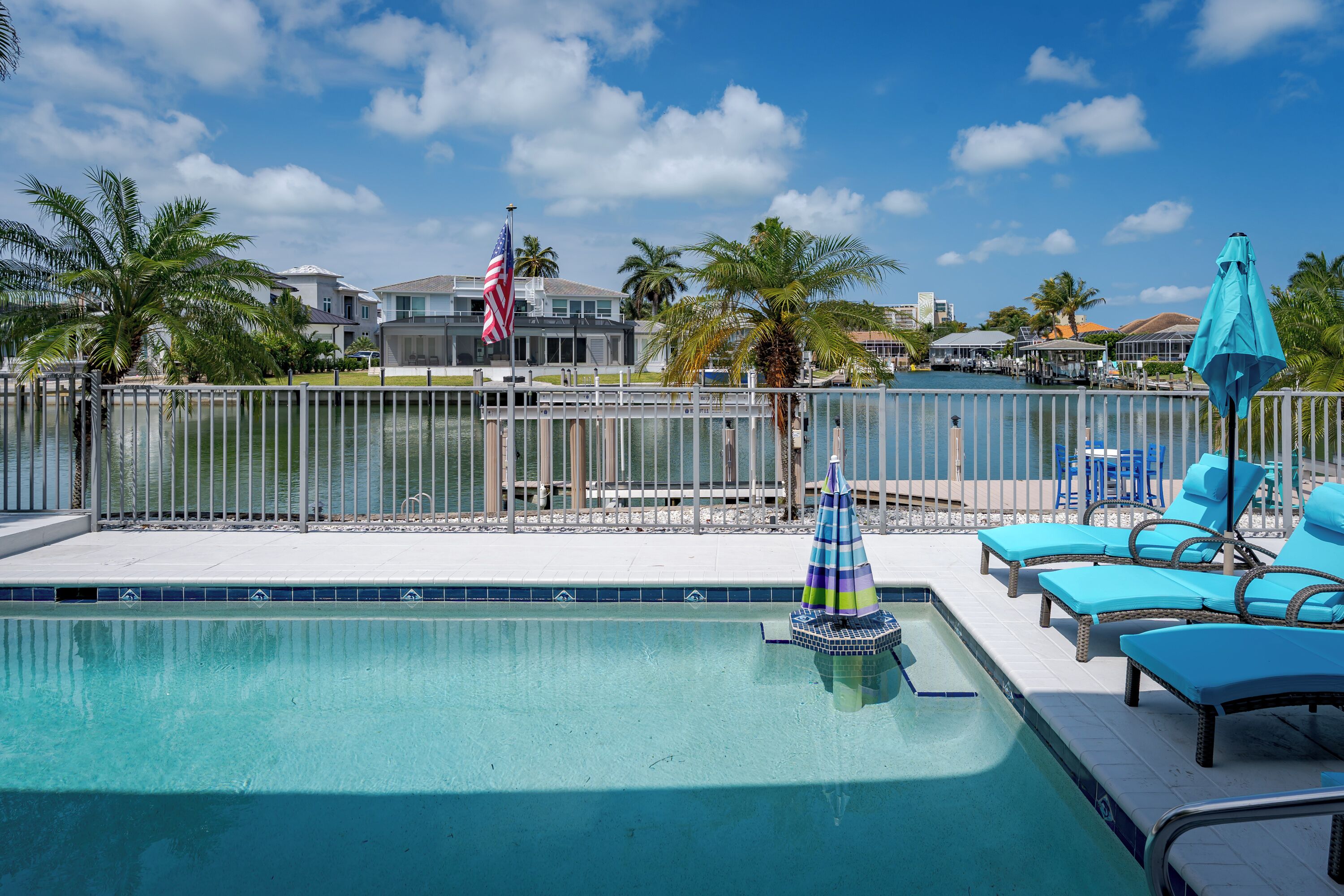 A swimming pool with lounge chairs and a flag.