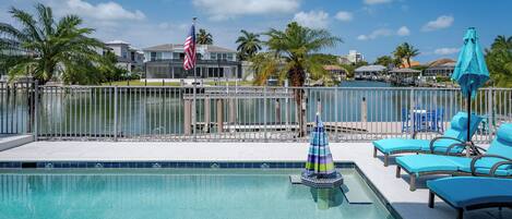 A swimming pool with lounge chairs and a flag.