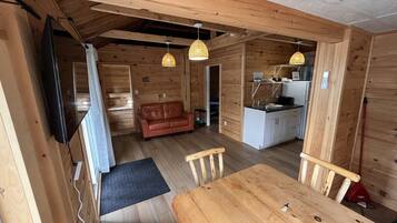 A wooden interior with a dining table, chairs, a sofa, and a kitchen area.