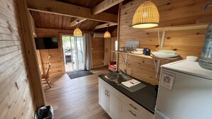 A wooden interior with a kitchen area, including a refrigerator, sink, and wooden cabinets. - Cozy Retreat For Two (Greater Sudbury)