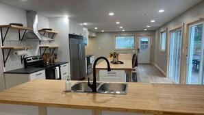 A modern kitchen with a central island, stainless steel appliances, and a view to the outside. - Fairbank Lake Cottages - Main Lodge (Whitefish)