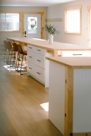 Una cocina moderna con una isla de madera, taburetes de bar y un jarrón con plantas.