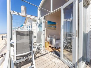 A balcony with a chair, a small table, and a bed with a view of the beach. - Beachhouse With sea Views in Dishoek (Koudekerke)