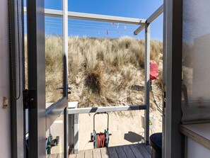 A beach house with a glass door leading to a deck, a small table, and a chair. - Beachhouse With sea Views in Dishoek (Koudekerke)