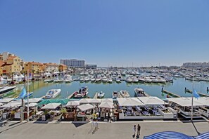 A marina with numerous boats docked, a waterfront café area, and a hotel in the background. - Marina Luxor 21 in Vilamoura (Loulé)